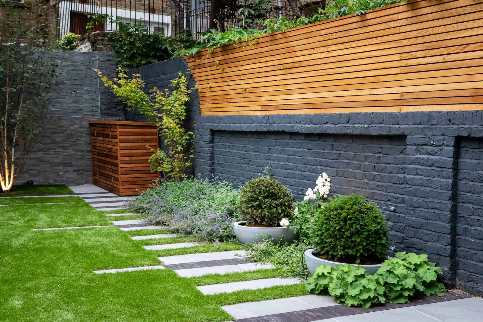 A fully renovated contemporary garden with a rendered wall, timber cladding and new planting